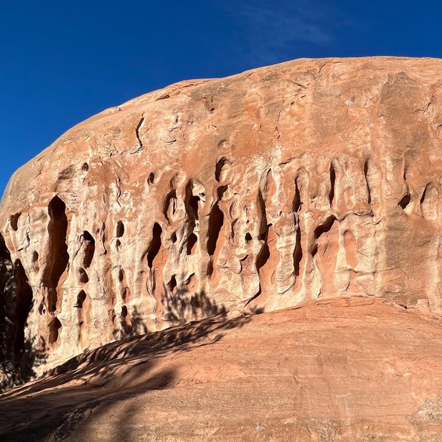 irregular holes in a salmon colored sandstone cliff