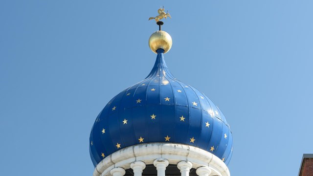 A blue Onion Dome with gold starts topped with a rampant colt. 