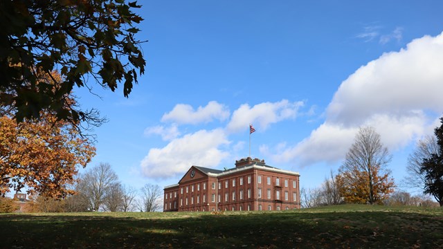 A multistory building with a flag on top of a hill. 