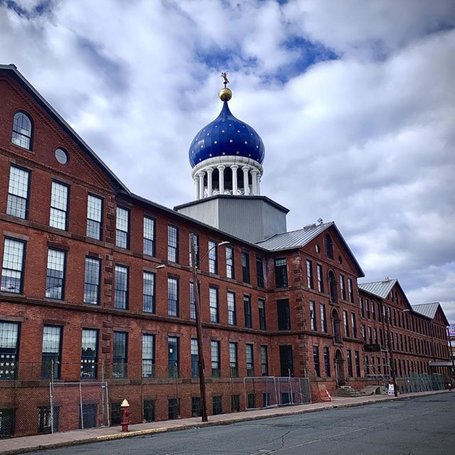 A multistory building with lots of windows and a blue onion dome on top. 