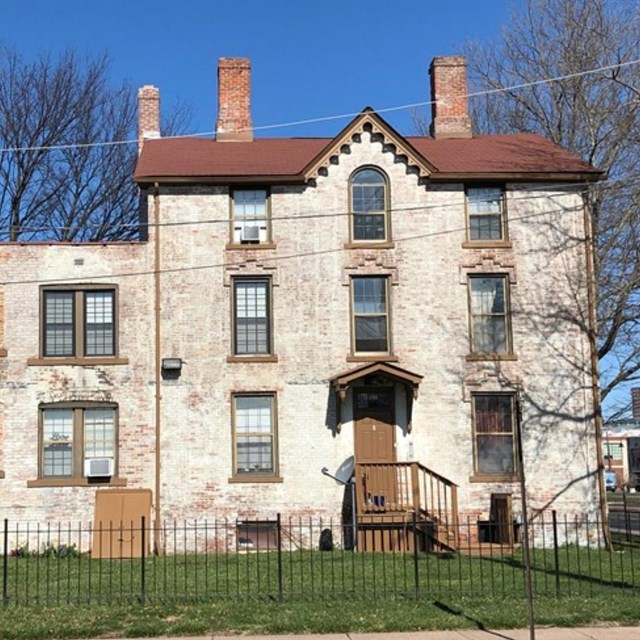 A multistory building with windows and a partially enclosed stairwell on the back. 