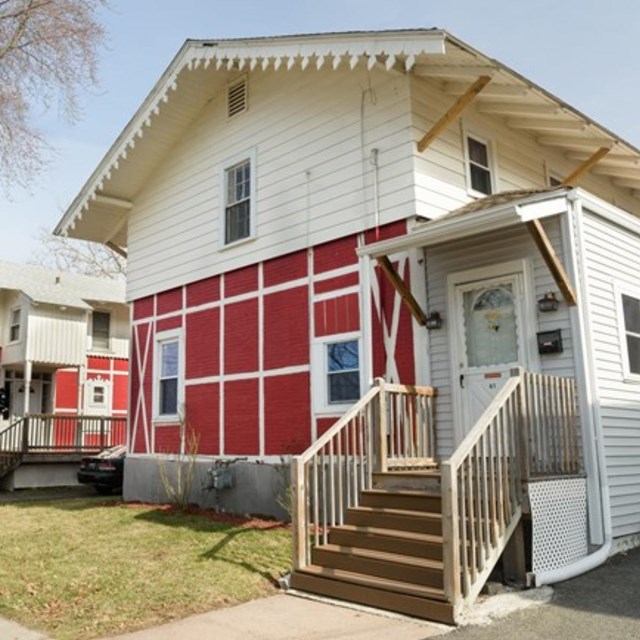 A red and white multistory building with steps at the front of the house. 