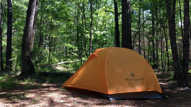 An orange tent sits under a green canopy in one of the park's campgrounds.