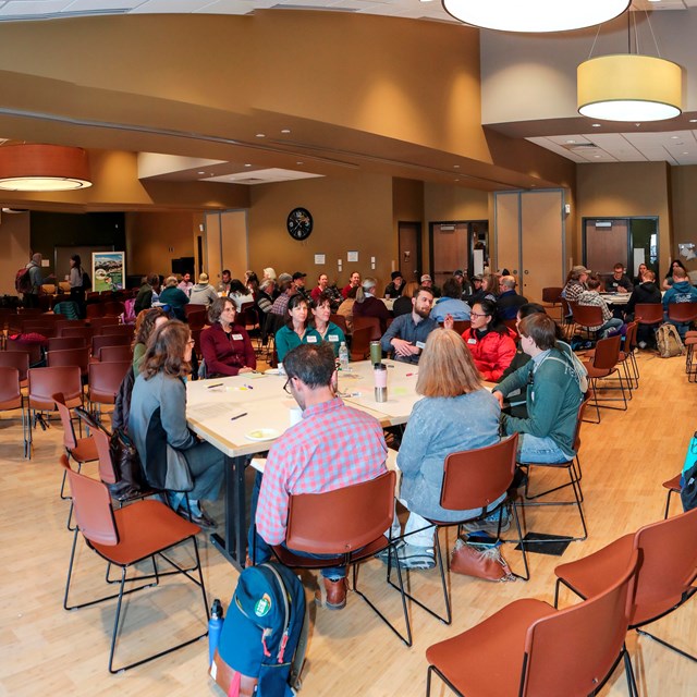 A room full of people at tables engaged in conversation. 