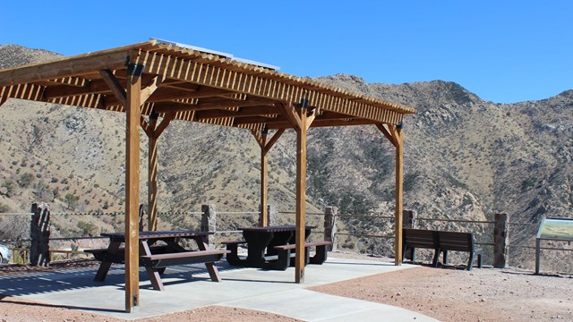 A ramada structure with sidewalk, mountain peaks in the background