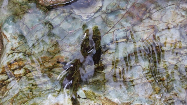 Water flows over blue hued stone