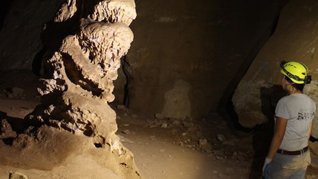 A cave explorer looks at a stalagmite 
