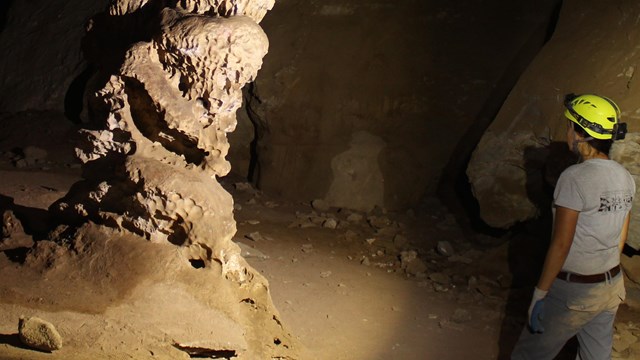 A cave explorer looks at a stalagmite 