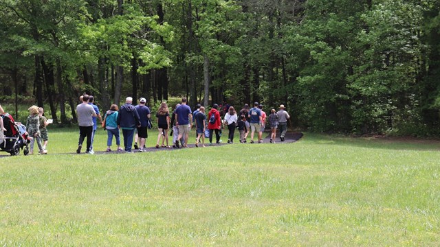 Ranger leads a battlefield tour on a paved path toward the woods