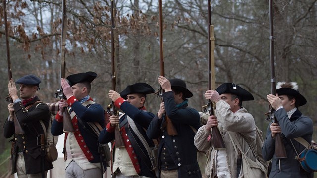 A cannon crew with a 3-pounder cannon after it has been fired.