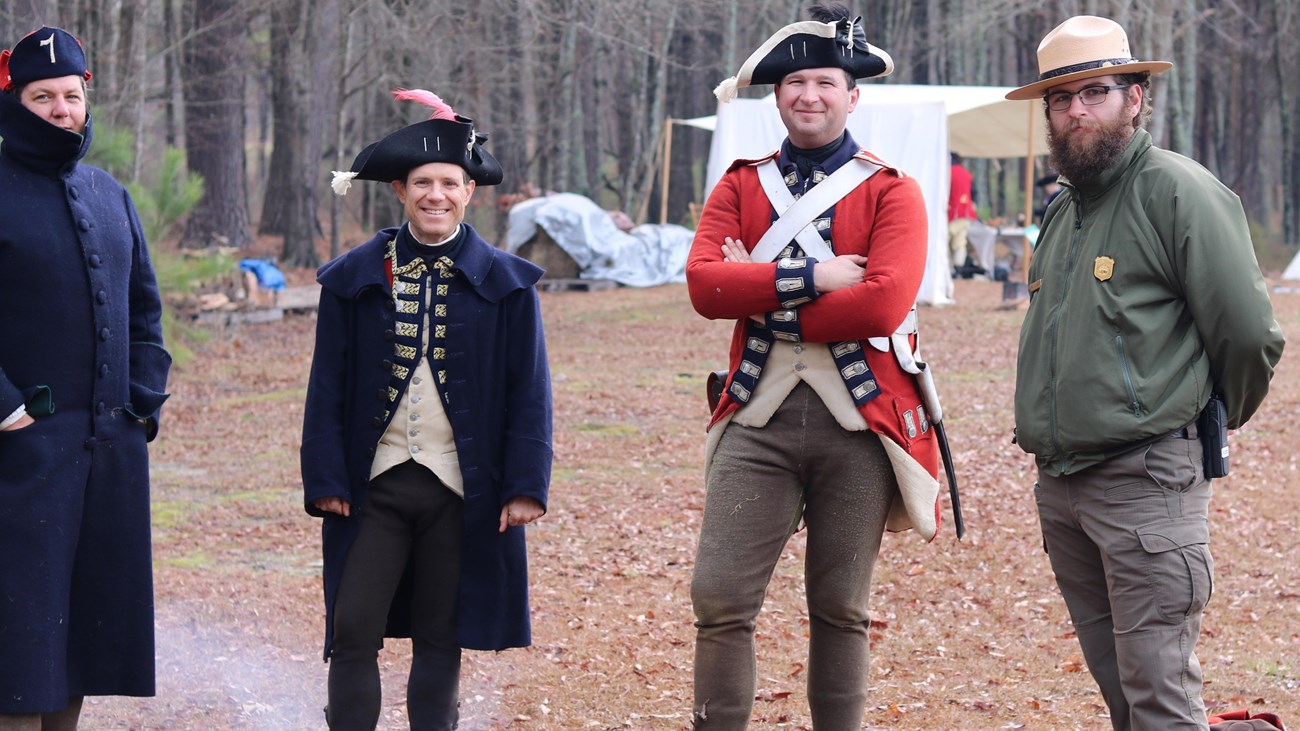 Photo of three reenactors and one Park Ranger