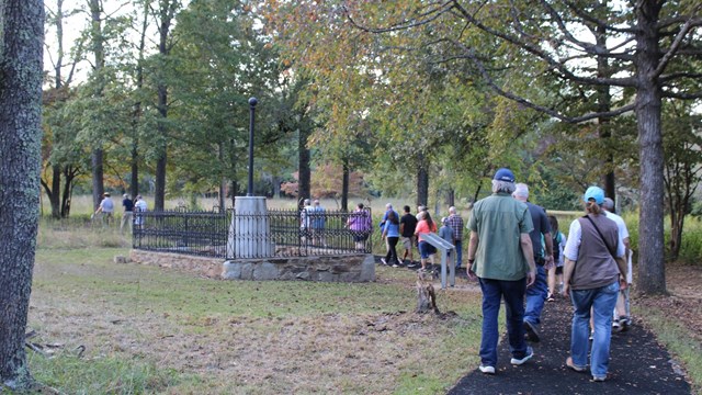 Ranger lead visitors on paved path into woods