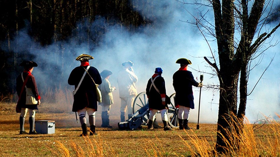 A cannon crew with a 3-pounder cannon after it has been fired.