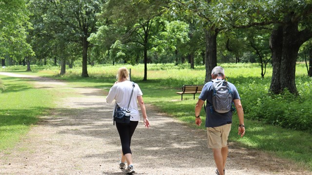 Two visitors walk down a dirt road