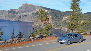 A blue car travels along the East Rim Drive.