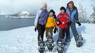 Kids pose in front of Crater Lake on a ranger-guided snowshoe walk.
