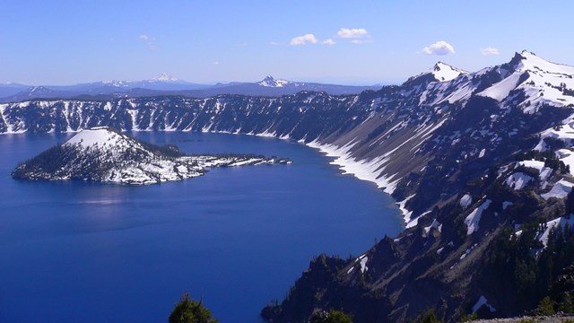 Crater Lake in June with lingering snow around the caldera and on Wizard Island