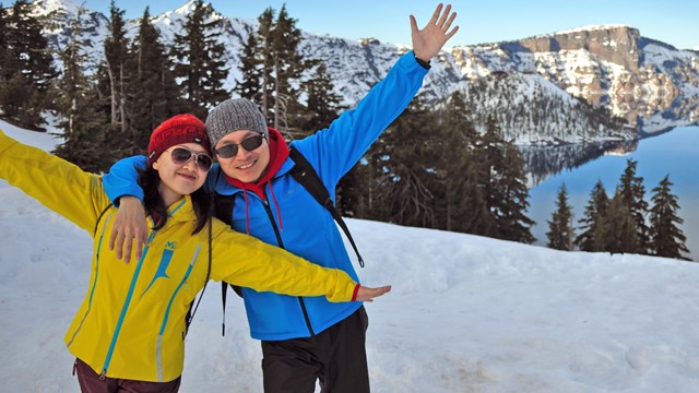 A happy couple poses in front of Crater Lake.