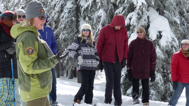 Visitors on snowshoes listening to a ranger