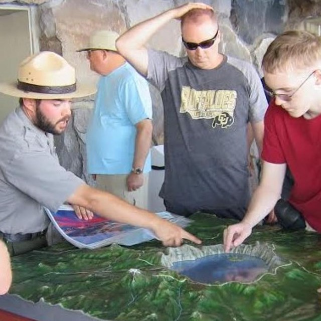 Visitors listen as ranger points to the Crater Lake on the relief map