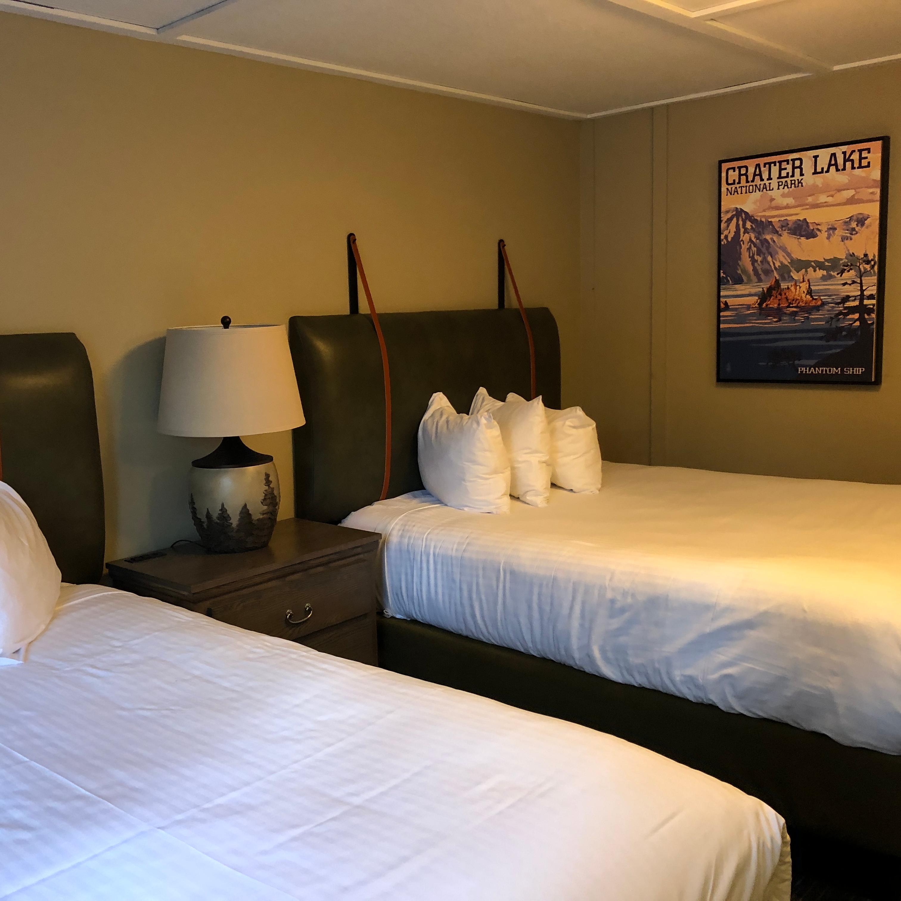 Cabin room, two queen size beds with white sheets & 3 pillows, framed print of Phantom Ship on wall 