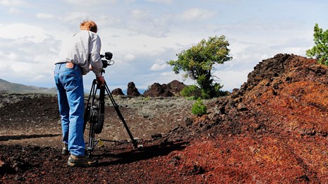 a man with a camera on a tripod filming the scenery