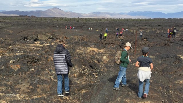 a group of students hiking across lava rock