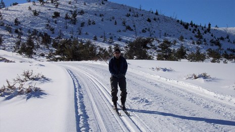 a person cross-country skiing down a groomed, snow covered road