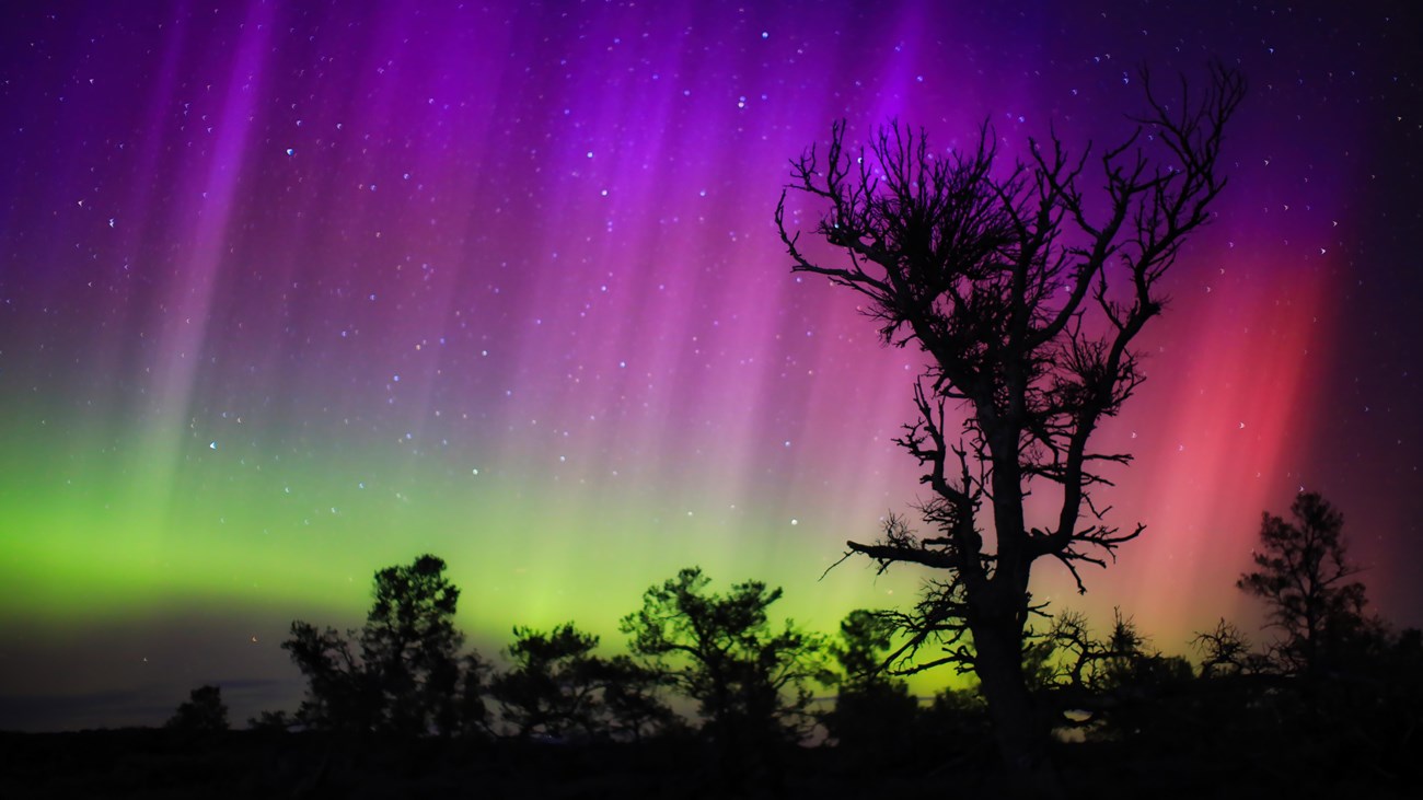 Northern Lights over silhouetted landscape. 