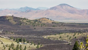 A panoramic shot of a volcanic landscape with a road running through it.