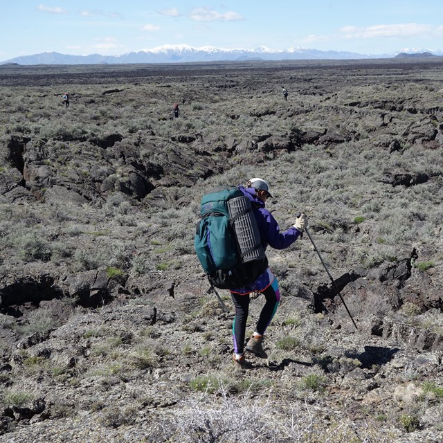 a hiker with a backpack walks across a vast, rocky landscape