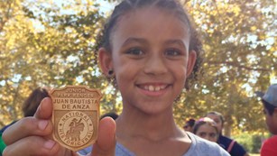 Kid holding up a Junior Ranger badge