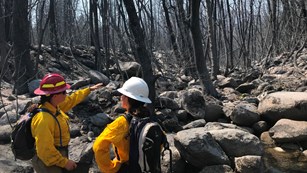 Two women firefighters talking at the base of a boulder debris flow