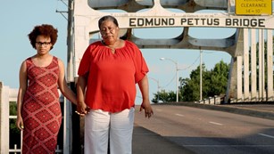 Two women holding hands standing at entrance to bridge