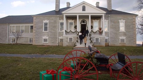 Sleigh with wrapped presents in front of a historic mansion