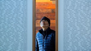 Man standing between two panels with long lists of names
