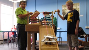 Two kids testing a wooden device on a slide