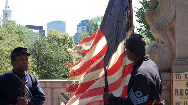 Two African American Civil War reeanctors holding a period U.S. flag