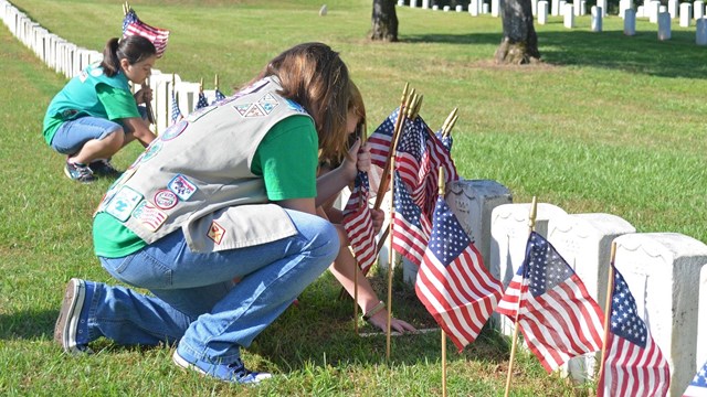 Several Girl Scouts placing flags on grave sites