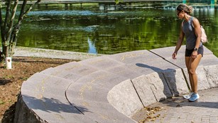 Visitor reading signatures engraved on a semi-circular stone memorial