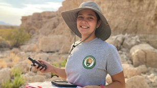 Geoscientist intern holding a GPS unit in the desert