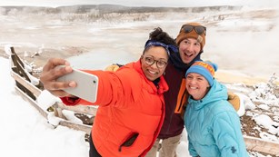 Three people taking a selfie in a snow-covered area 