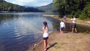 Small group of girls fishing on a riverbank