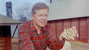 Historical photo of Jimmy Carter on a farm holding a handful of peanuts