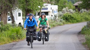 Two bicyclists on a path by an RV campground