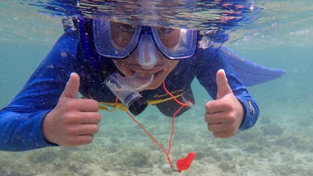 Kid snorkeling and giving the camera two thumbs up
