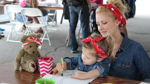 Women holding child coloring in a book
