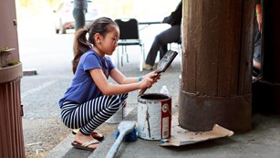 Child volunteer painting a structure