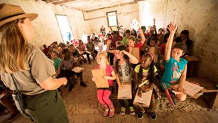 Ranger talking to a group of students seating on rows of benches in a building