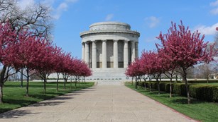 View of memorial rotunda down stone path flanked by pink flowering trees